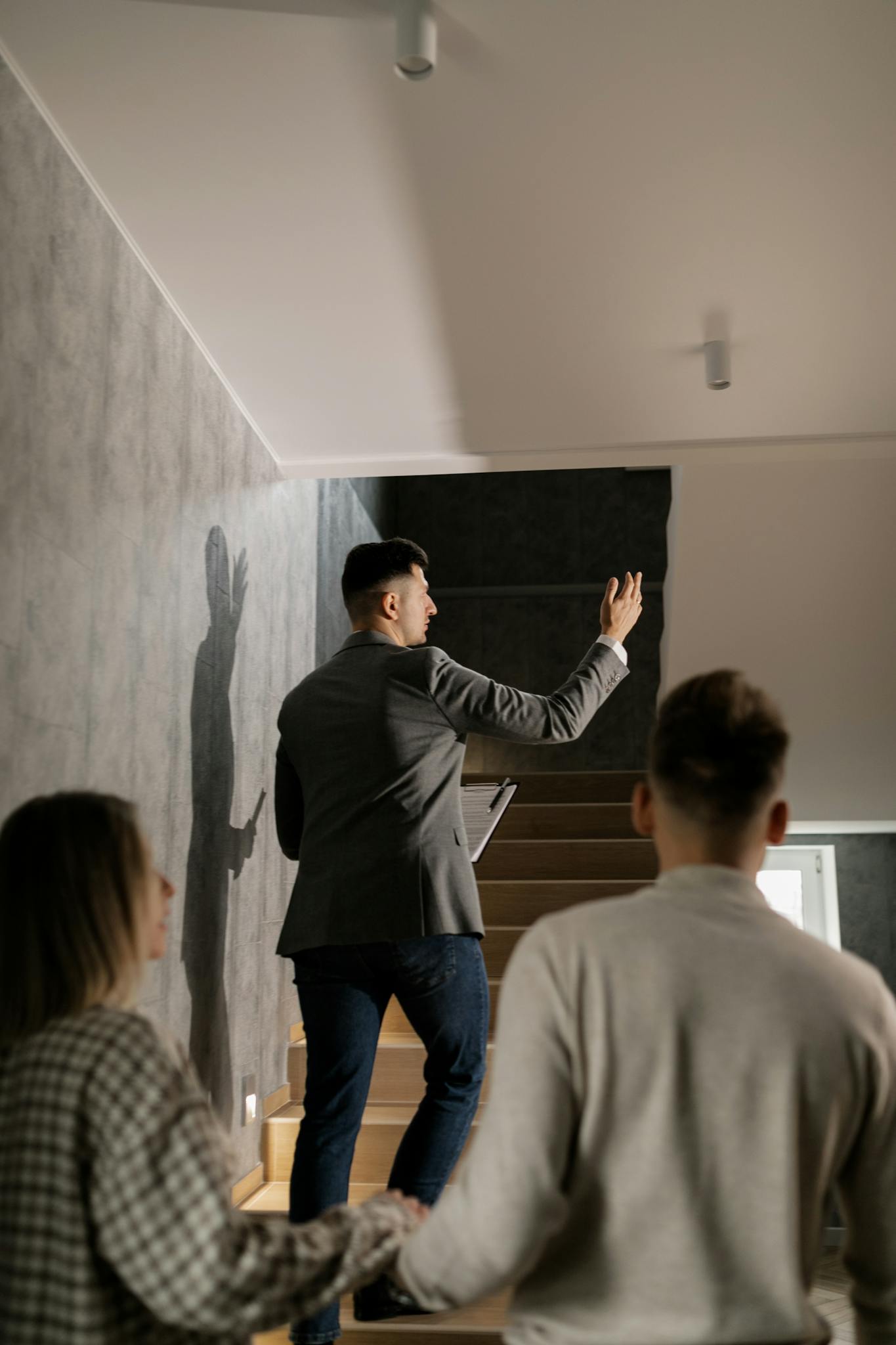 A real estate agent leads a couple on a house tour, highlighting interior features in a modern home.