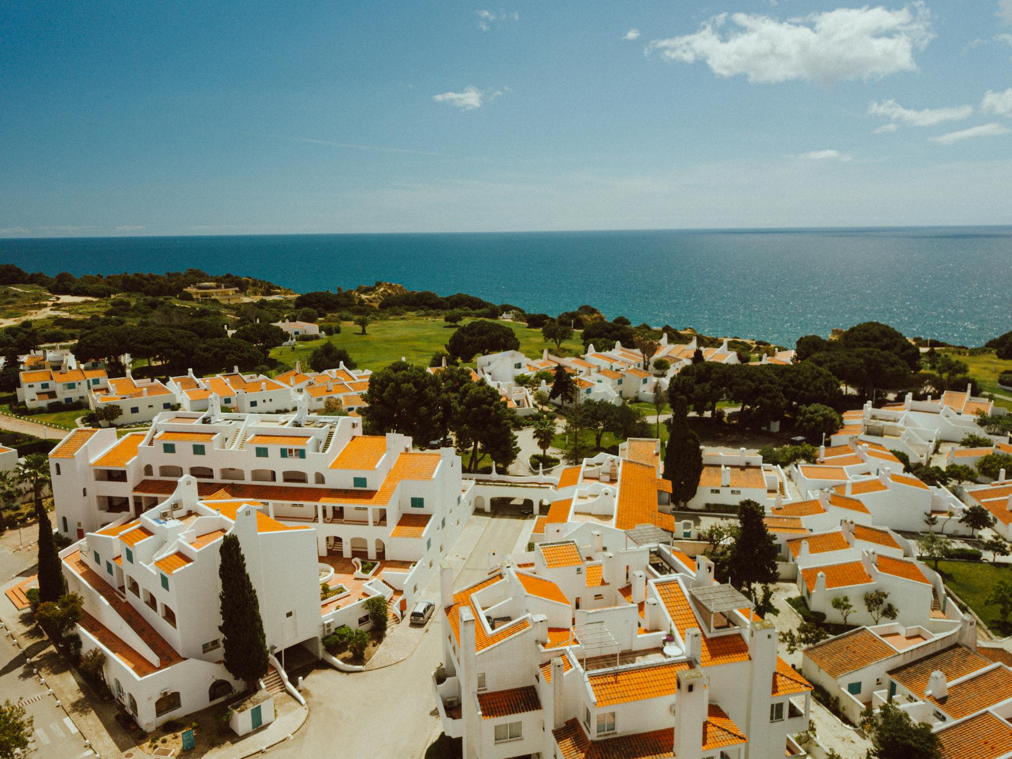 Aerial shot of Algarve's picturesque coastline with white villas and orange roofs overlooking the sea.