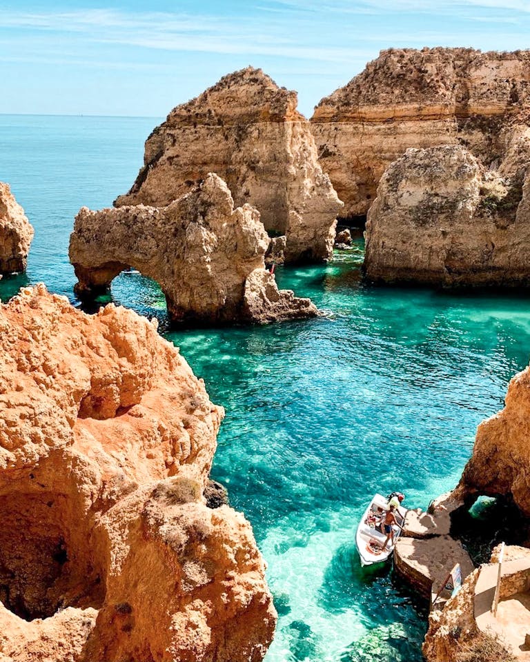 Explore stunning rock formations along the Algarve coast with clear blue waters and a serene boat ride.