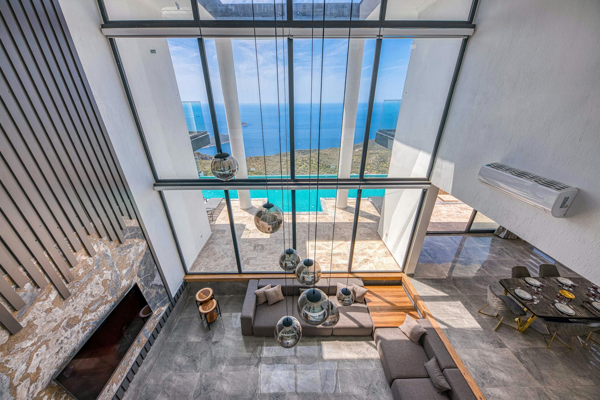 Spacious villa interior with stunning ocean view through large windows, elegant decor.