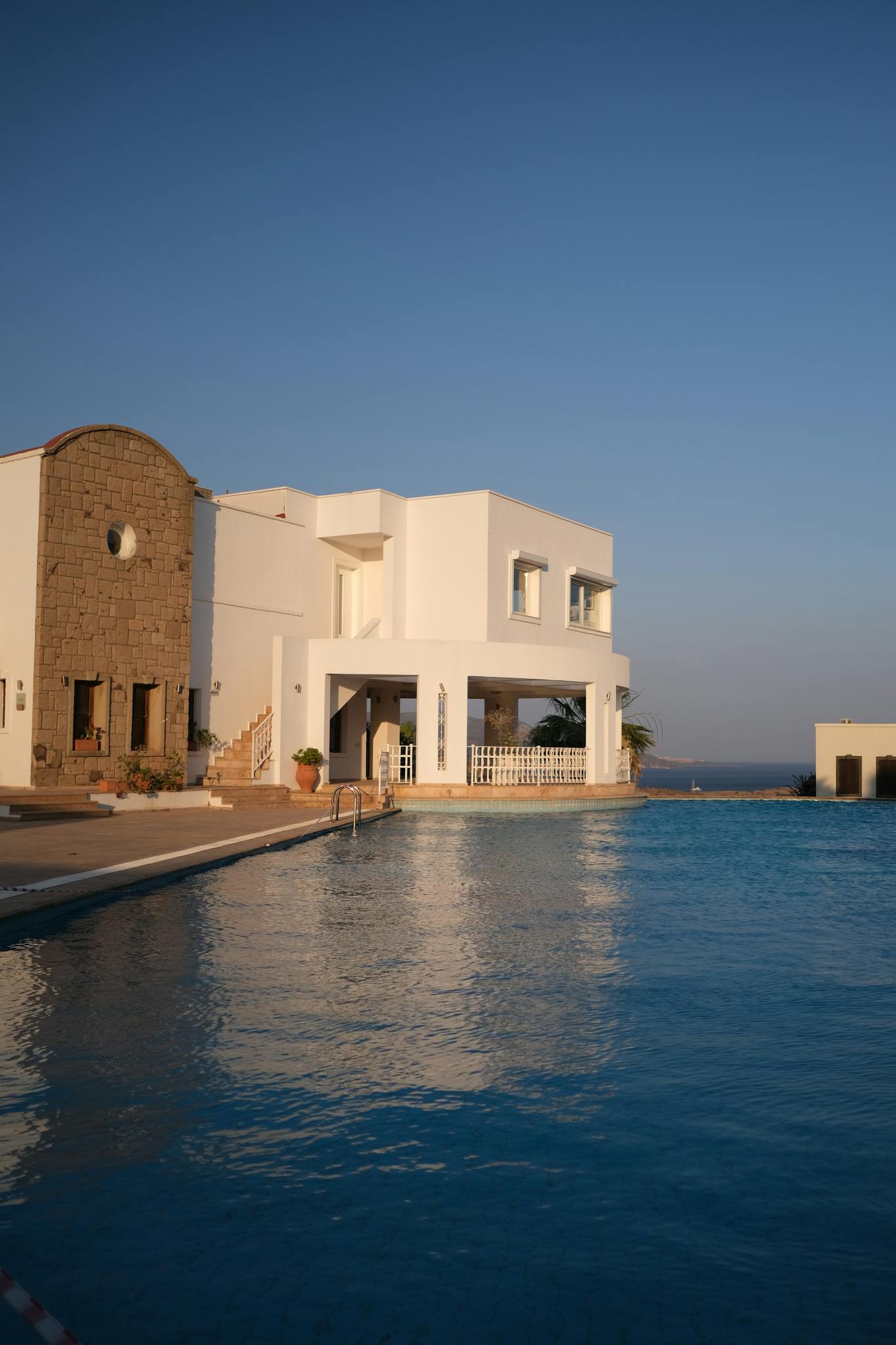 Stunning Mediterranean villa with poolside view and ocean backdrop at sunset.