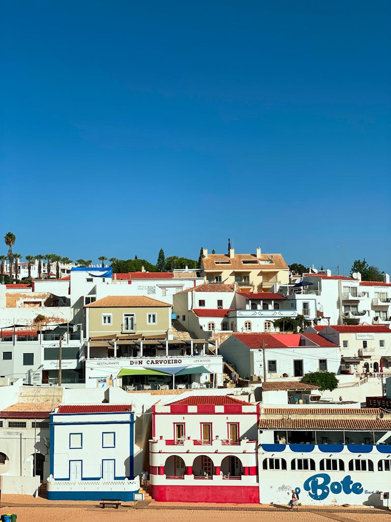 Vibrant coastal houses in Carvoeiro, Portugal under a clear summer sky.