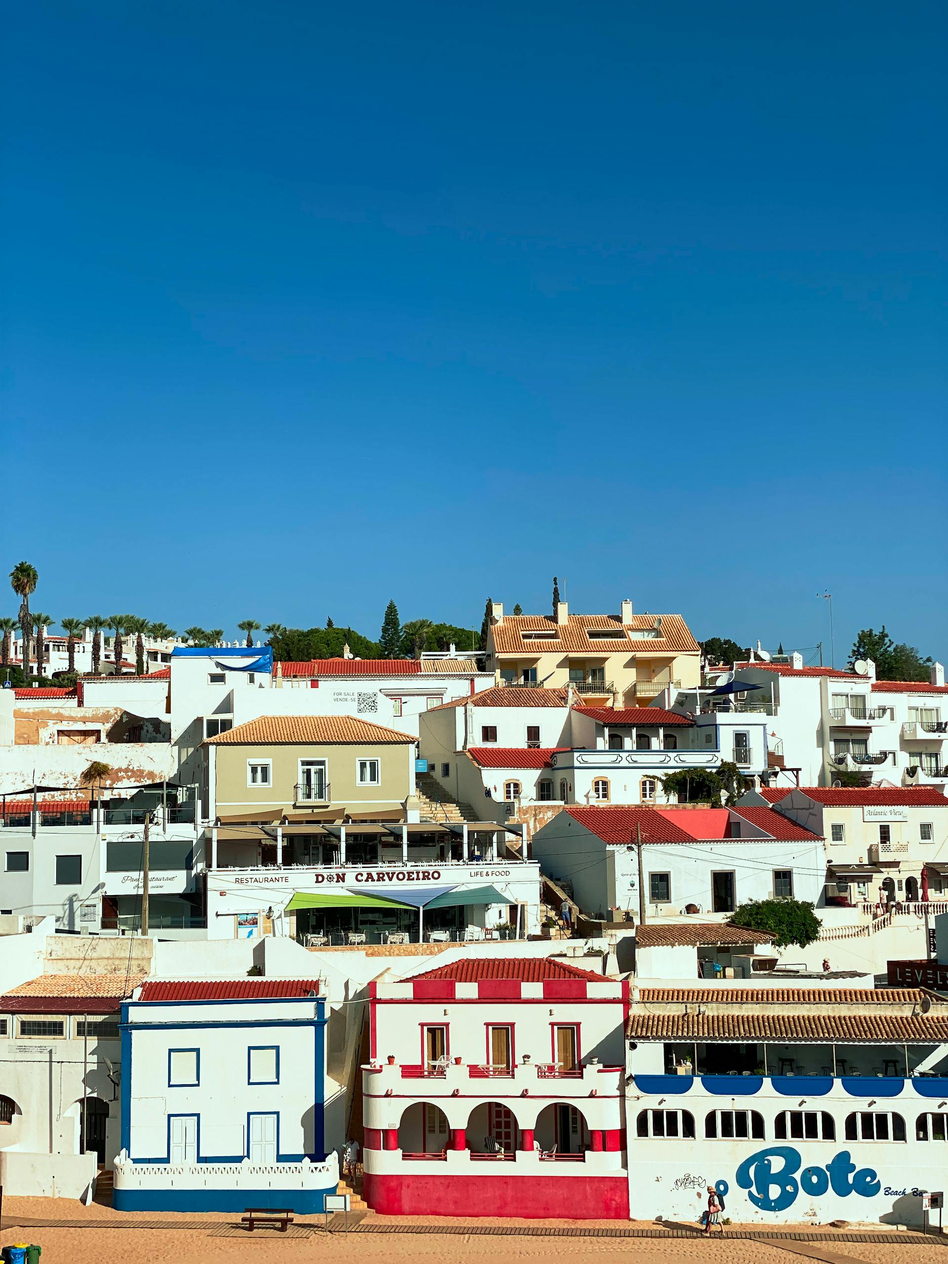 Vibrant coastal houses in Carvoeiro, Portugal under a clear summer sky.
