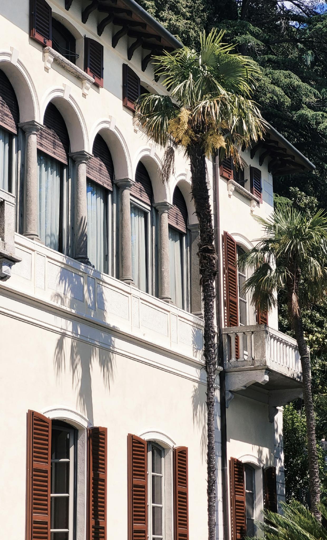 A beautiful Mediterranean-style villa with palm trees, showcasing classic architecture and lush greenery.